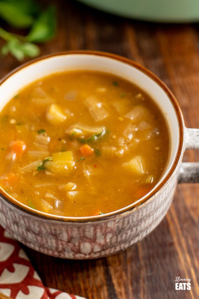 a close up of a bowl of soup on a table with a spoon and napkin