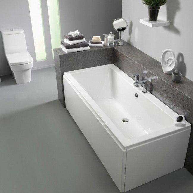 a white bath tub sitting in a bathroom next to a toilet and sink with towels on the wall