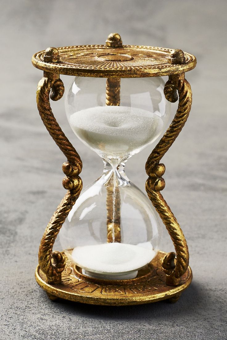 an hourglass with sand in it sitting on a table next to a gray surface