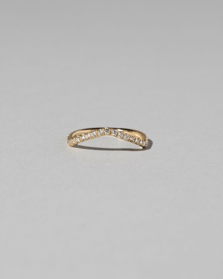 a yellow gold wedding band with small diamonds on the side, set against a plain grey background