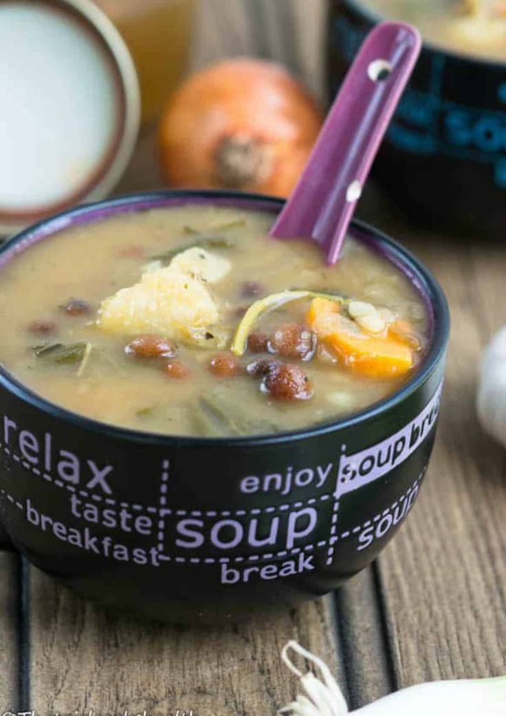 a bowl of soup is sitting on a table next to some vegetables and other foods