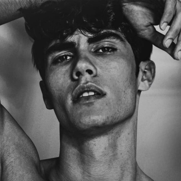 a black and white photo of a shirtless man with his hands on his head