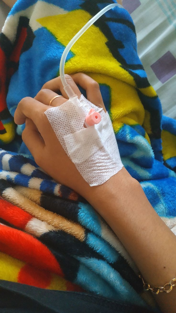 a person with an iv in their hand on a colorful blanket and wearing a cast