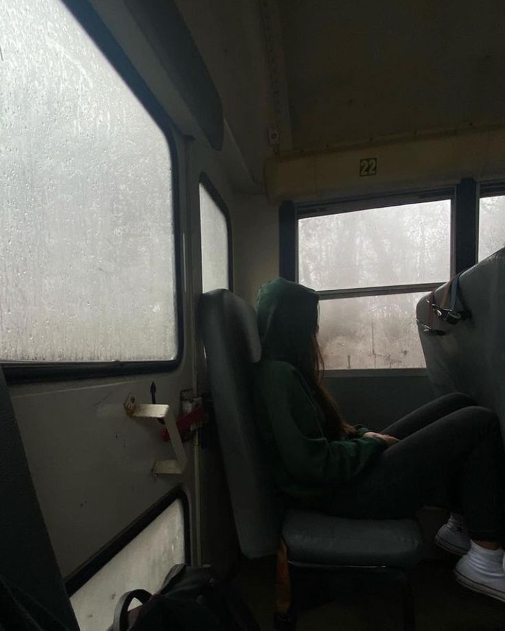 a person sitting on a bus with their back to the camera and looking out the window