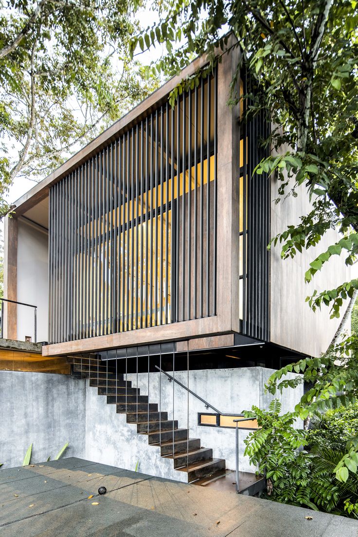 the stairs lead up to the upper level of this modern house, which is surrounded by trees