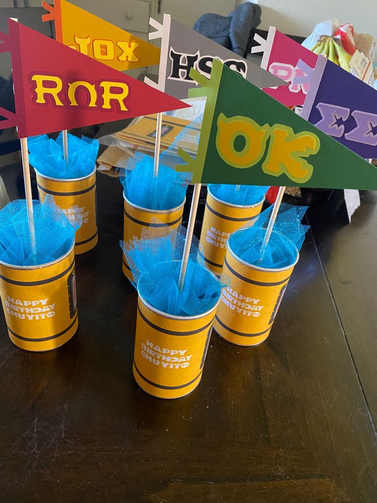 cups with blue pom - poms are sitting on a table in front of colorful signs