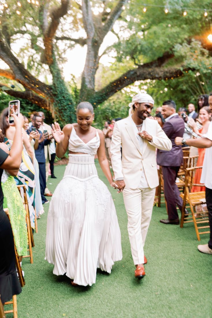 a bride and groom walking down the aisle after their wedding ceremony at an outdoor venue