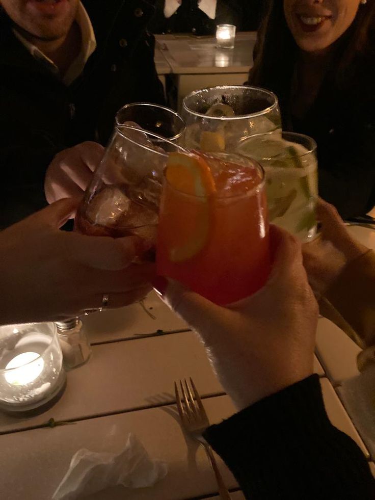 people are holding up glasses with drinks in them