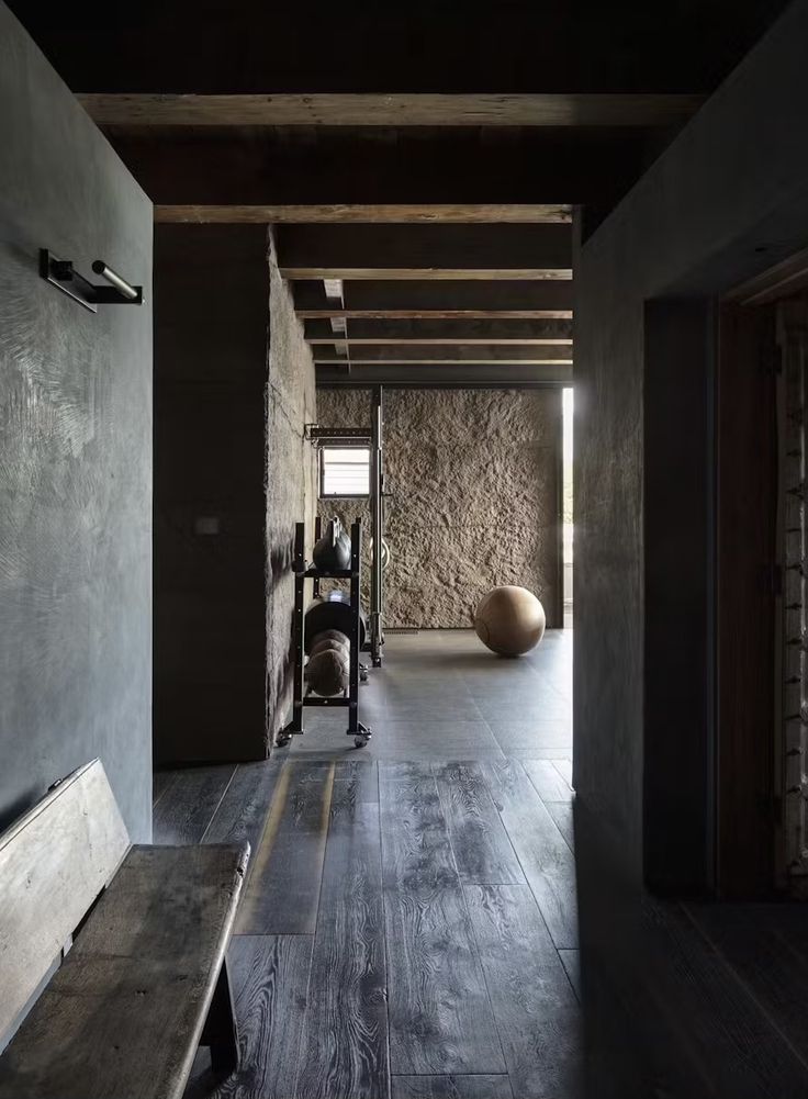 an empty room with a wooden bench and stone wall