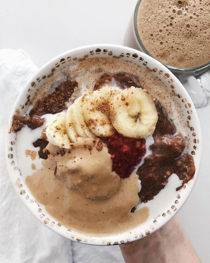 a person holding a bowl of food next to a cup of coffee