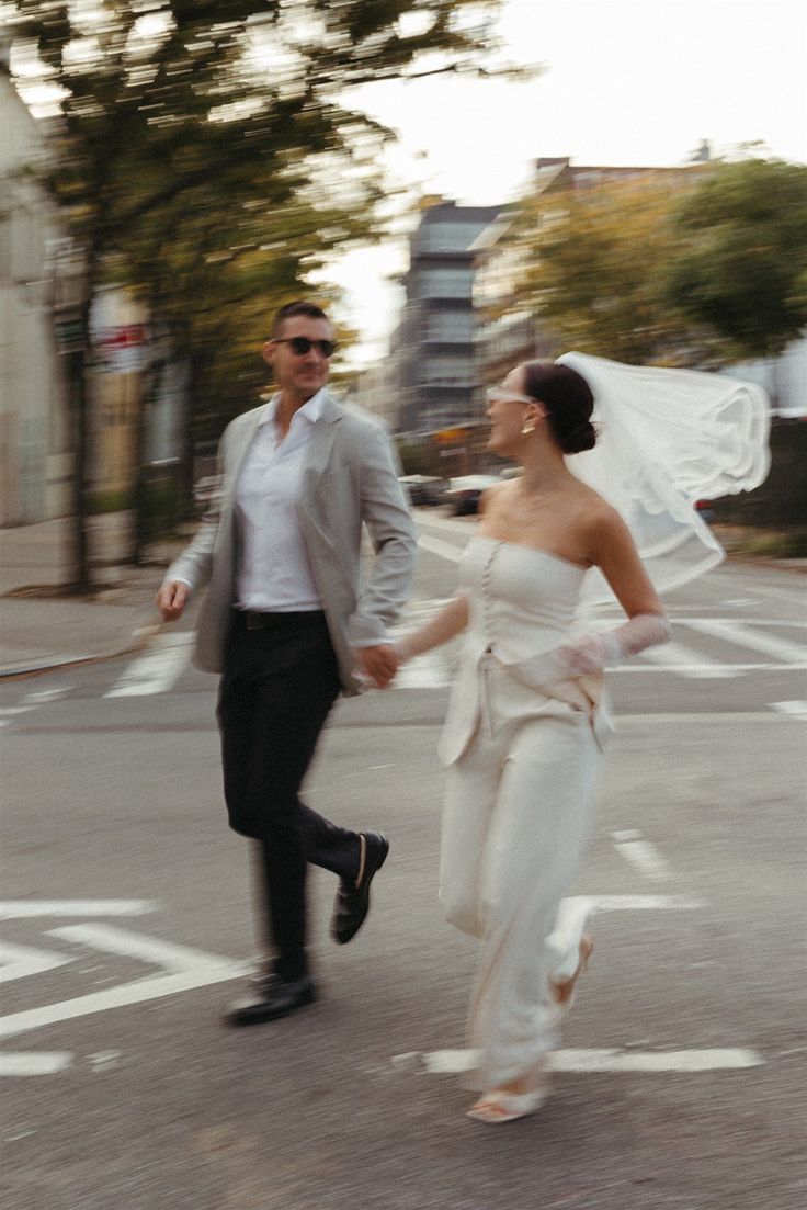 a bride and groom crossing the street holding hands