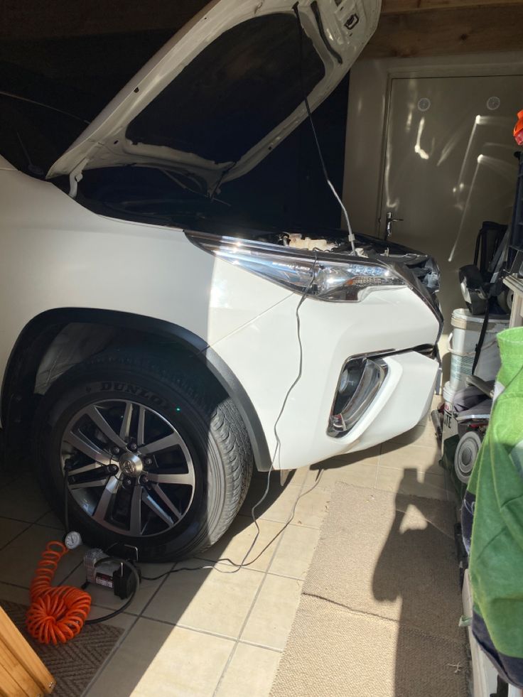 the front end of a white car with its hood open