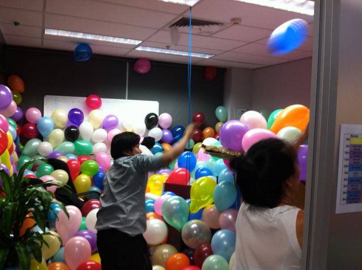 two people standing in front of a bunch of balloons