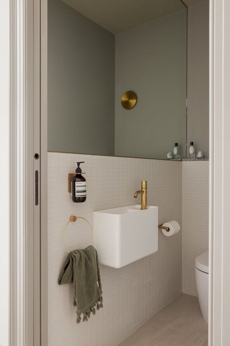 a bathroom with a sink, mirror and toilet paper roll hanging on the wall next to it