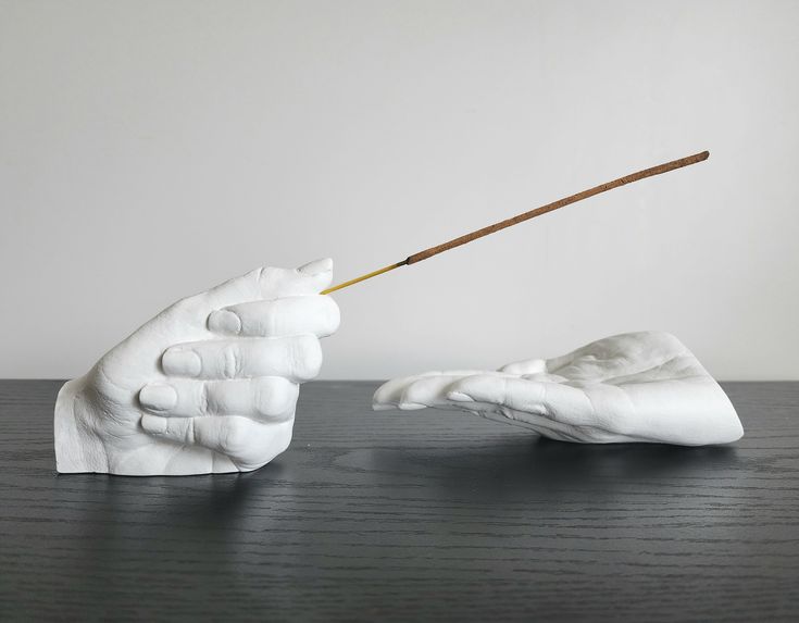 a white sculpture holding a stick in it's hand on top of a wooden table