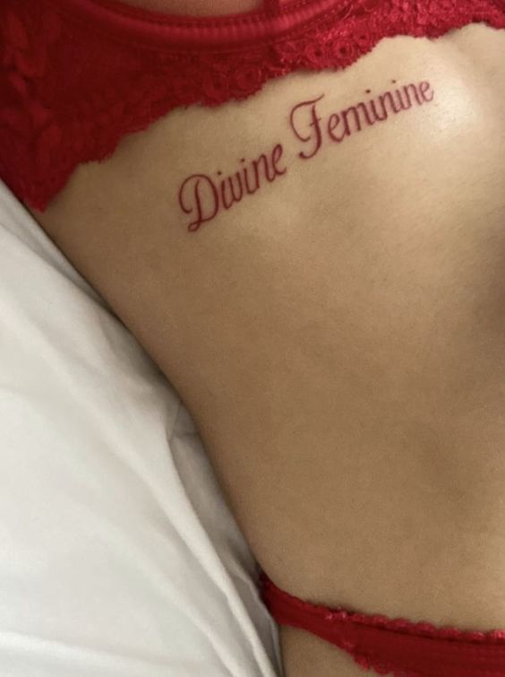 a woman with a tattoo on her back saying divine feminine