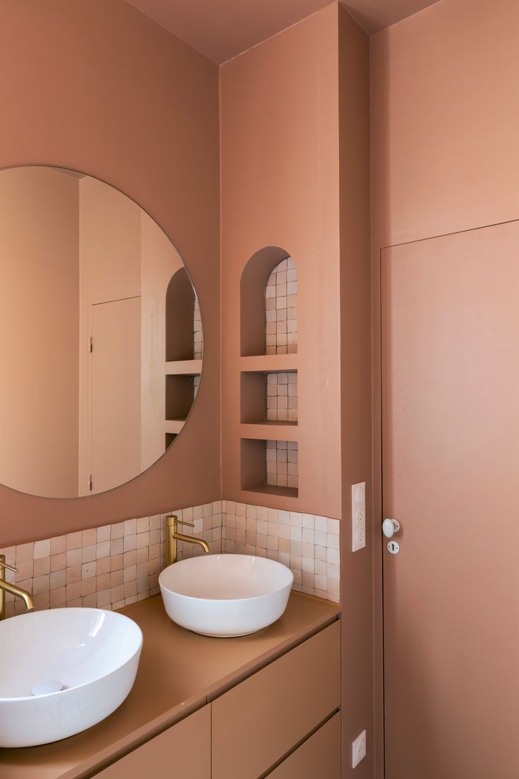 a bathroom with two sinks and a round mirror