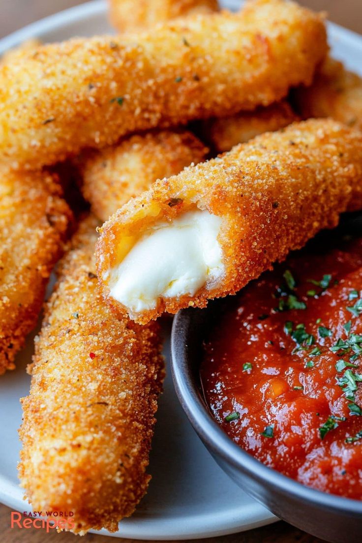 some fried food on a white plate with sauce and parmesan cheesesticks