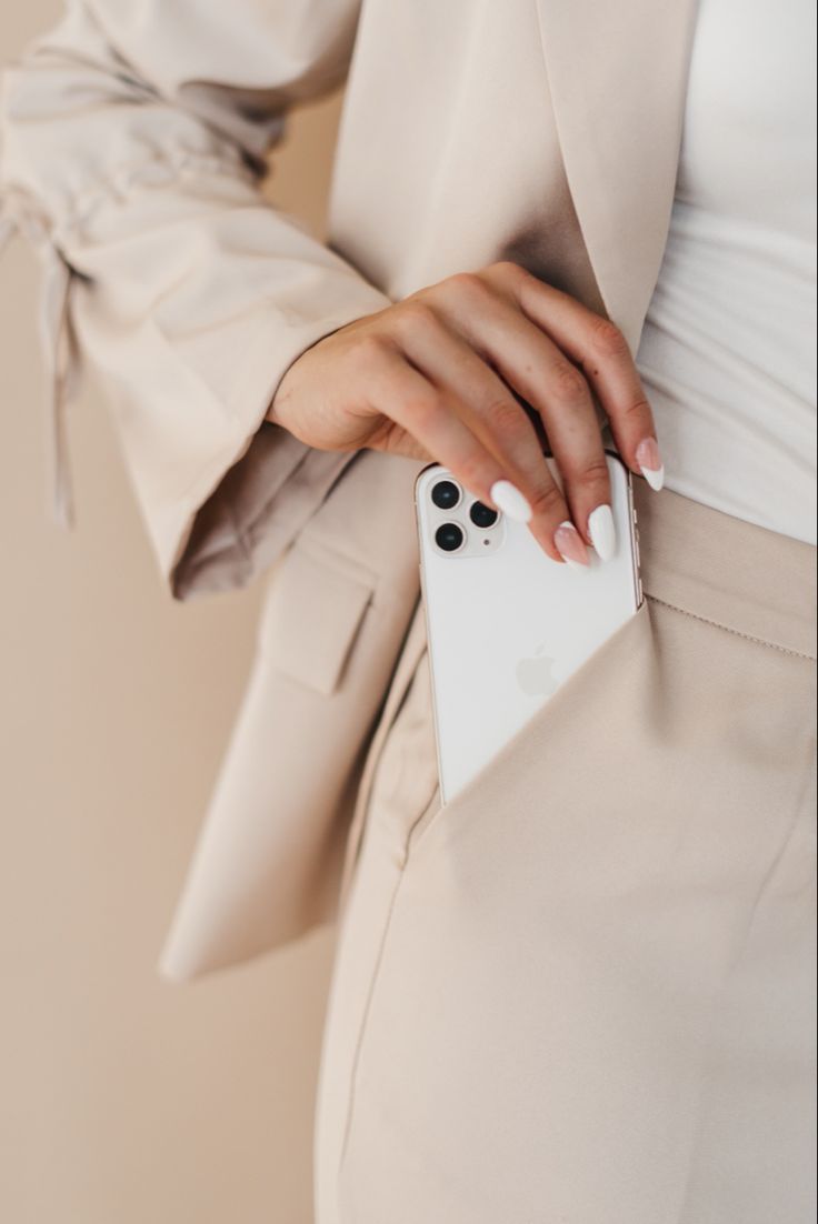 a woman is holding an iphone case in her hand and wearing a white coat with black polka dots on it