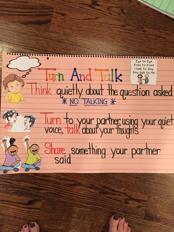 a child's hand holding up a pink paper with writing on it that says turn and talk