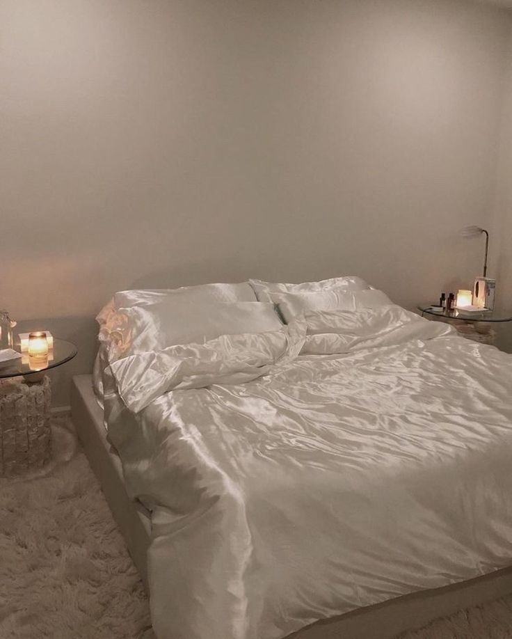 a white bed sitting in a bedroom next to two candles