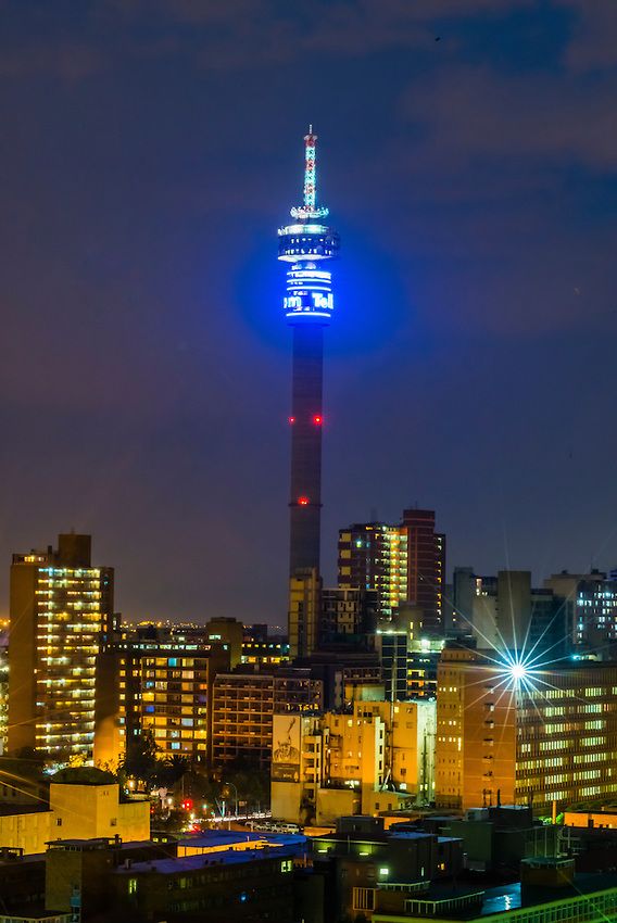 a very tall building with a bright blue light on it's side at night