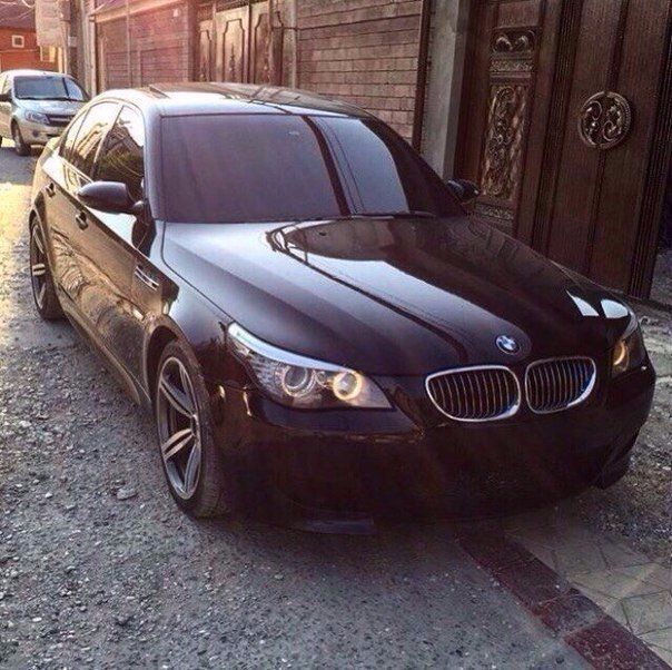 a black car parked on the side of a road next to a brick wall and door