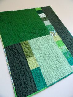 a green and black patchwork quilt on a white table