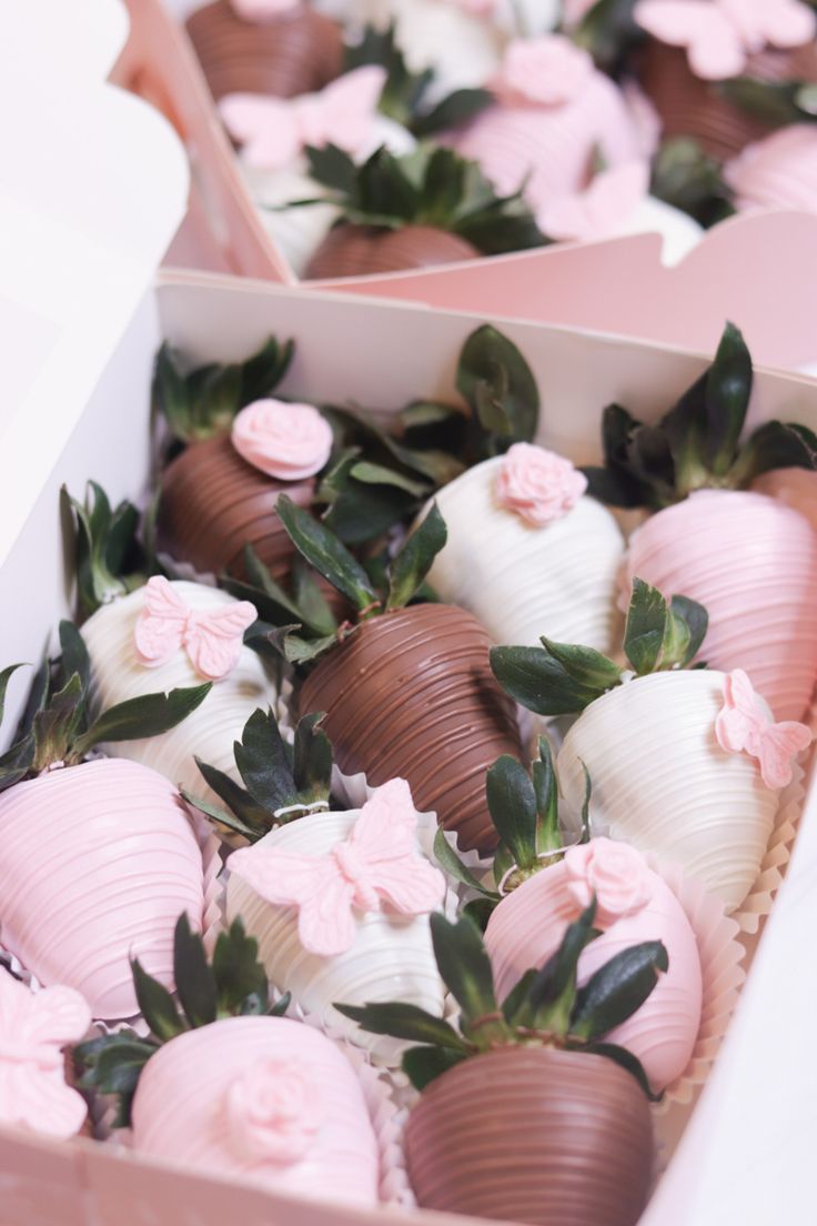 chocolate covered strawberries in a box with pink flowers on top and white frosting