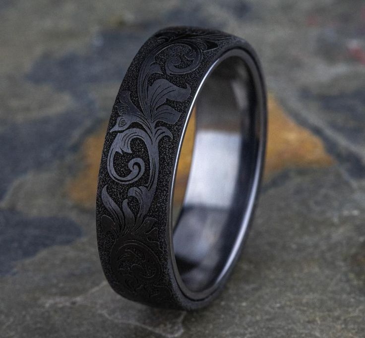 BENCHMARK Men's Wedding Band THE PALACE Style Number: RIRCF1265391 Vintage script pattern Color: Grey Tantalum and Black Titanium Available Metals: Tantalum Width: 6.50mm, 8.00mm Comfort-Fit: Yes Starting Price: $590.00 USD* This Item Can Be Engraved Upon Request *The possibilities are not limited to the options in the dropdown. For pricing on further customizations & special size options, please call: 1-586-939-5100 Men's Rings Black, Men Engagement Ring Black, Cool Mens Engagement Rings, Mens Gothic Rings, Black Band Rings Men, Black And Silver Rings For Men, Vintage Wedding Rings For Men, Mens Black Rings, Goth Wedding Men