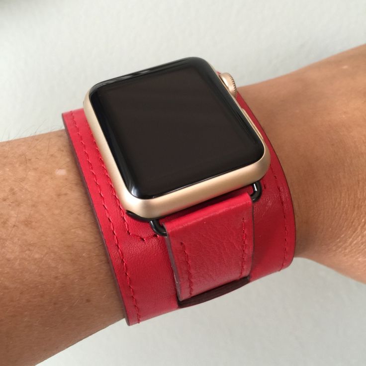 a person wearing a red leather wristband with an apple watch on it's arm