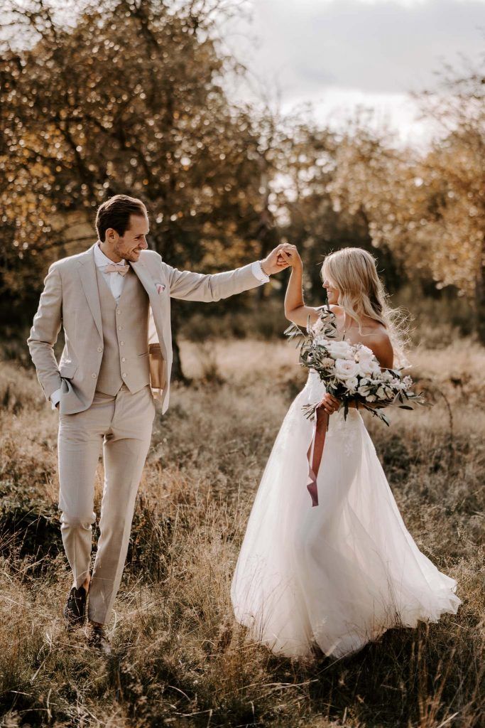 a bride and groom are walking through the field