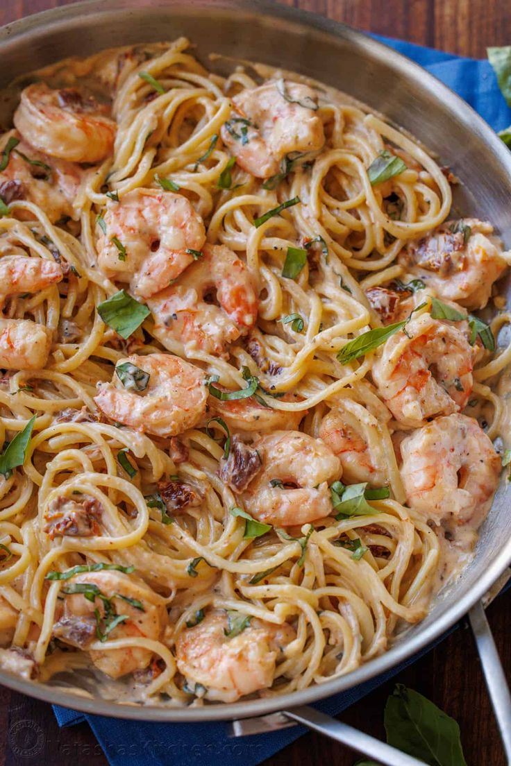 a pan filled with shrimp and pasta on top of a wooden table