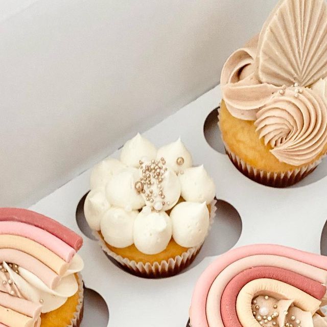 four cupcakes decorated with different designs and colors