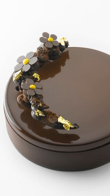 a chocolate cake with yellow flowers on it's top, sitting on a white surface