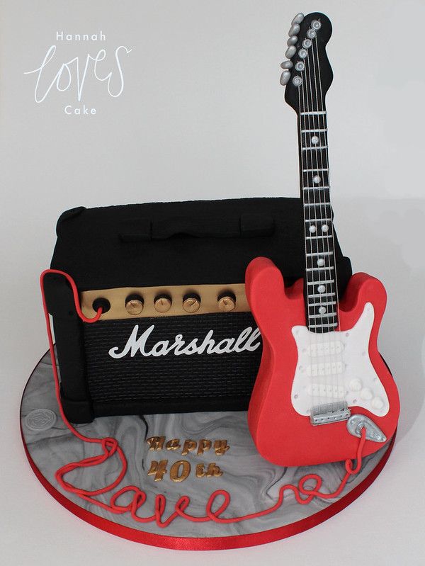 a red guitar cake sitting on top of a table next to a black and white amplifier