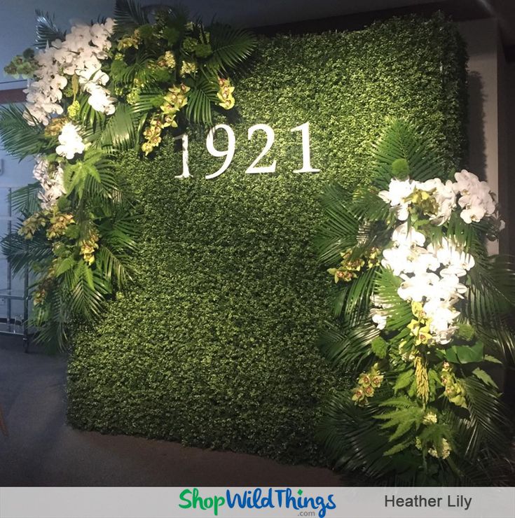 a green wall with white flowers and greenery in front of it that reads 1932