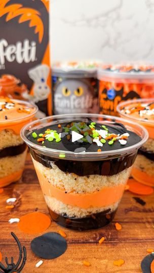 halloween desserts in plastic cups with sprinkles and candy on the table