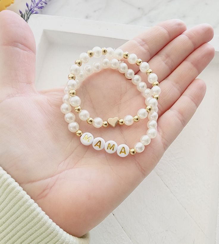 two personalized bracelets in gold and white pearls on a woman's hand