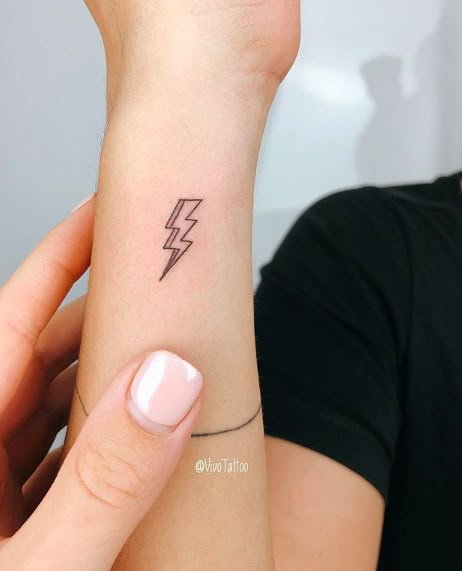 a woman's arm with a small lightning tattoo on the left side of her wrist