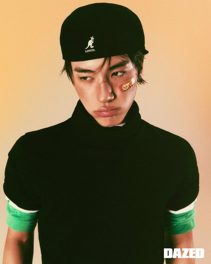 a young man wearing a black hat and green shirt with the word dazed written on it