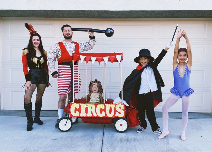 three people dressed up as circus performers posing for a photo in front of a garage