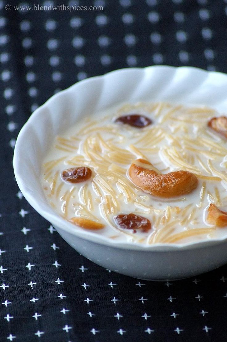 a white bowl filled with food on top of a black cloth covered table next to a fork