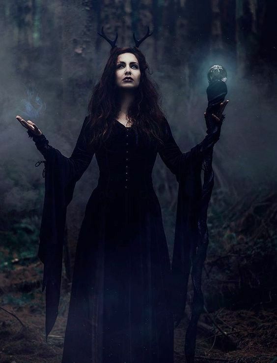 a woman dressed in black holding a crystal ball with horns on it's head