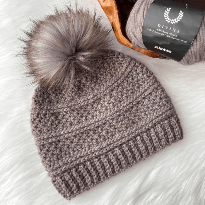 a gray knitted hat with a grey pom - pom