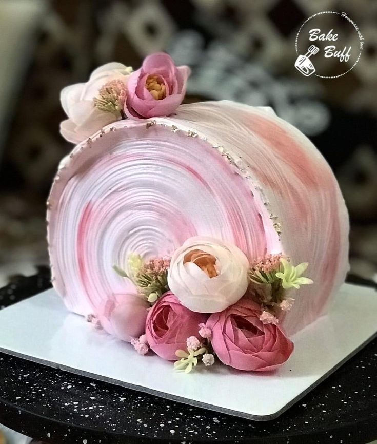 there is a pink cake with flowers on the top and sides, sitting on a white plate