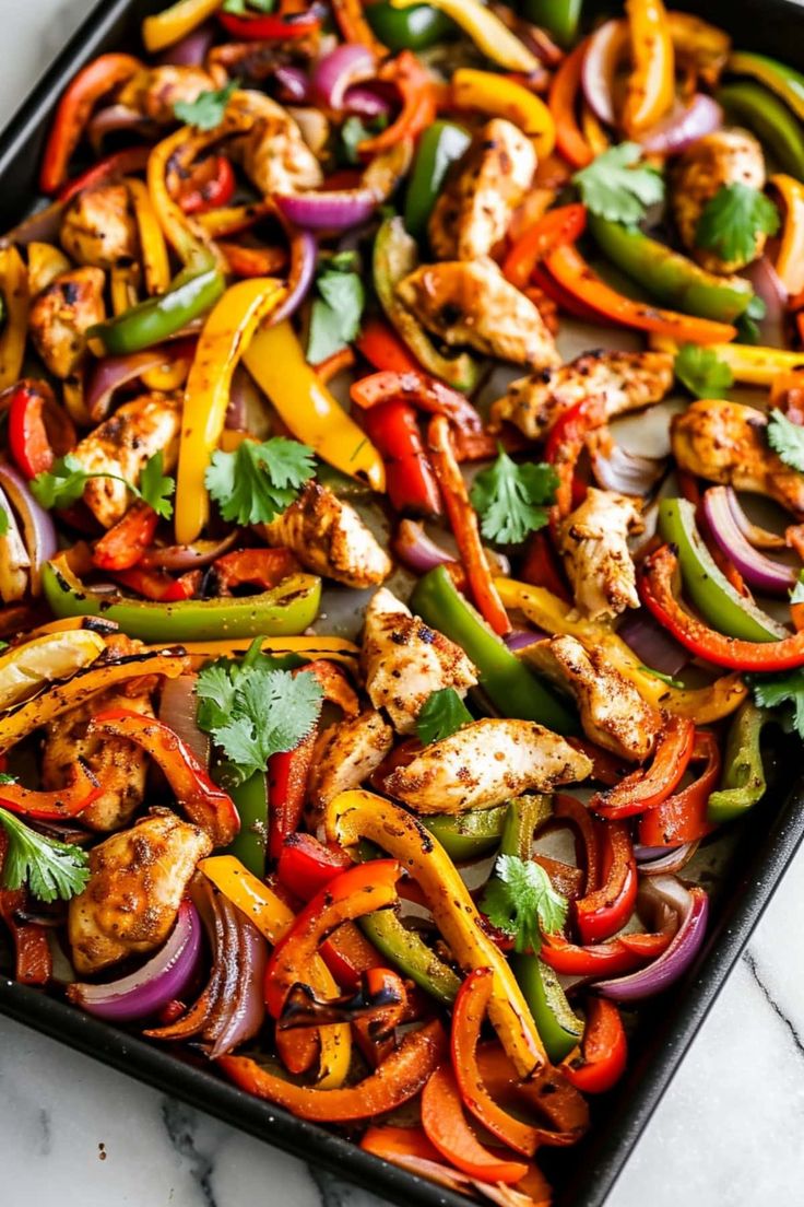 chicken fajita with peppers, onions and cilantro on a baking sheet