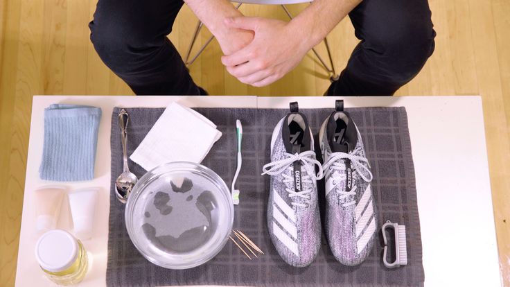 a person sitting at a table with some shoes and other items around him on the table