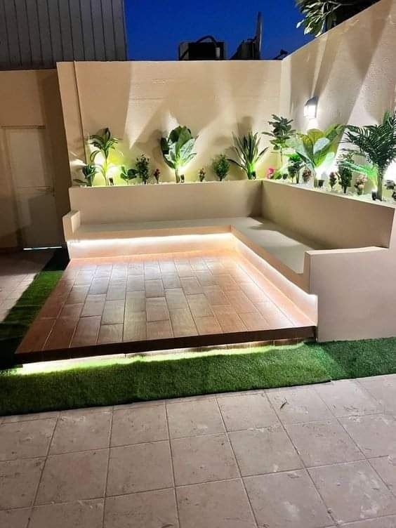 an outdoor area with artificial grass and plants on the walls, lights in the middle