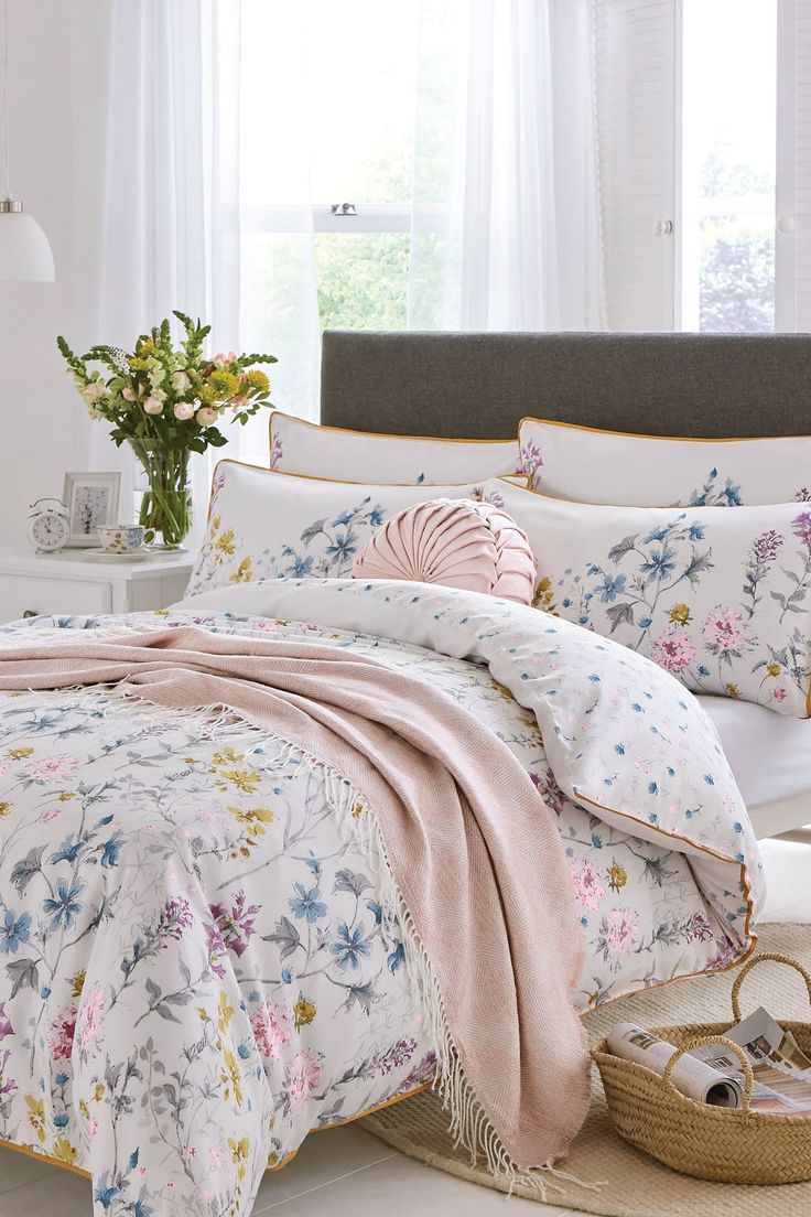 a bedroom with white walls and flowers on the comforter, along with a bed